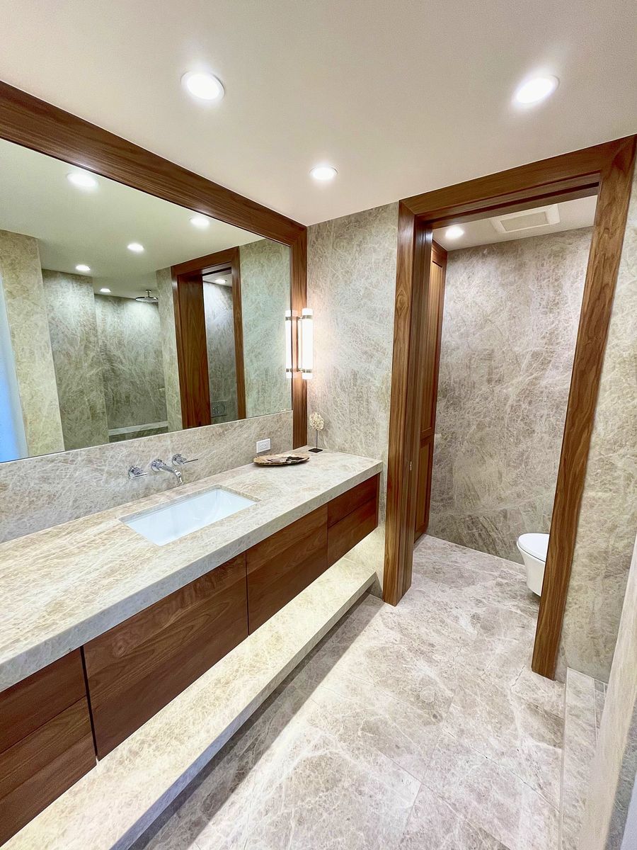 Floating walnut vanity with stone countertop and stone walls