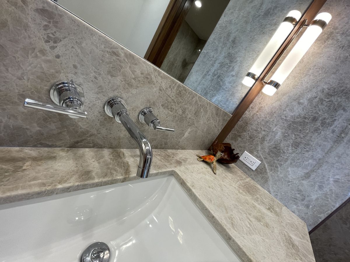 Wall-mounted polished chrome faucet over a Taj Mahal quartzite counter