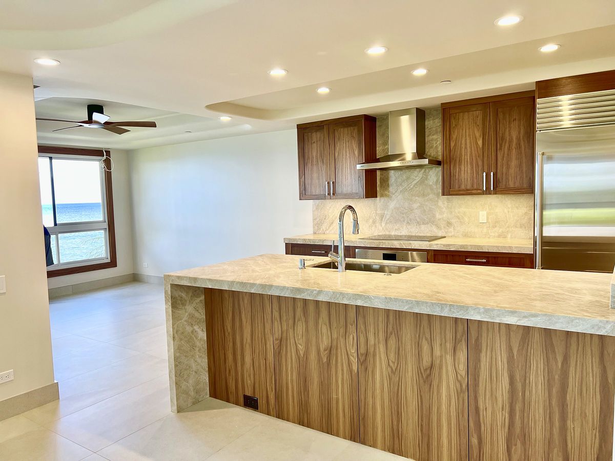 Open kitchen with walnut cabinetry and a stone waterfall island